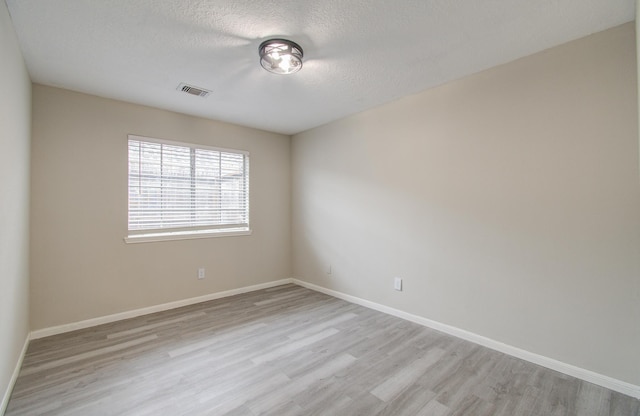 spare room with a textured ceiling and light wood-type flooring