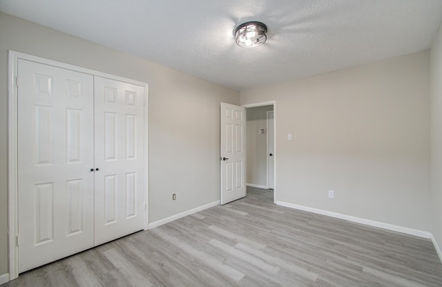 unfurnished bedroom featuring light hardwood / wood-style floors, a textured ceiling, and a closet