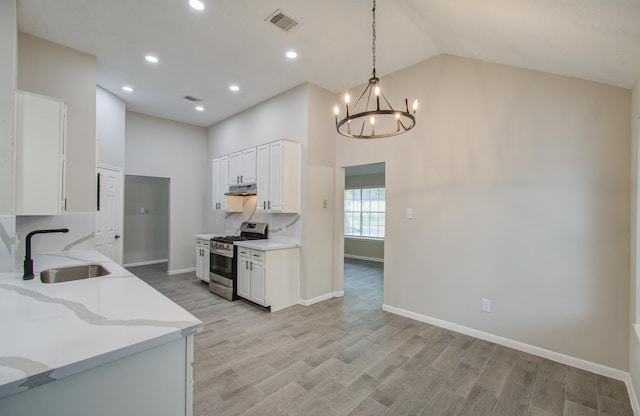 kitchen featuring white cabinets, sink, pendant lighting, light stone counters, and stainless steel range with gas cooktop