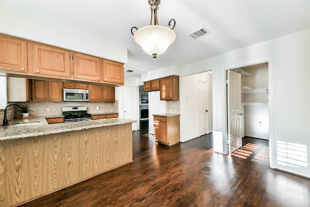 kitchen with sink, decorative light fixtures, backsplash, light stone counters, and stainless steel appliances