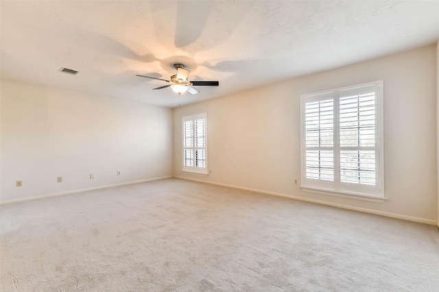 empty room with ceiling fan, plenty of natural light, and light colored carpet