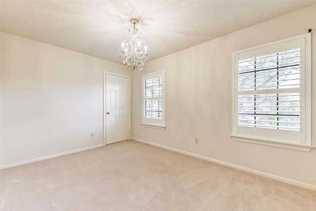 carpeted empty room featuring a notable chandelier