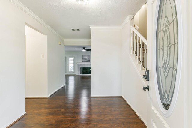 entryway with a brick fireplace, ornamental molding, dark hardwood / wood-style flooring, and a textured ceiling