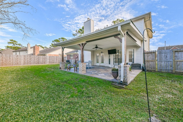 rear view of property featuring ceiling fan, a yard, and a patio