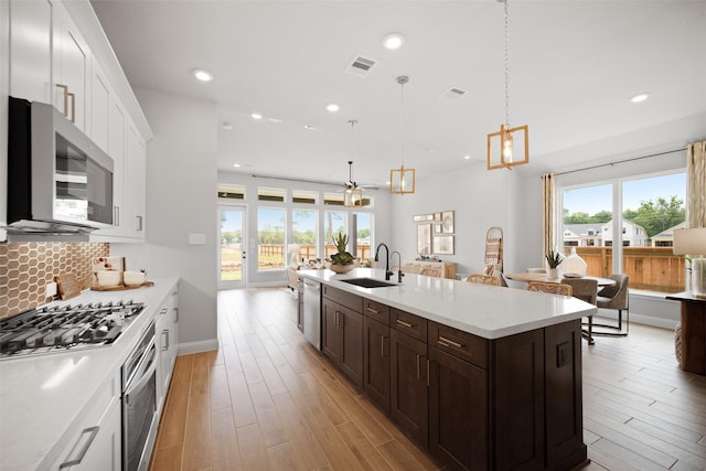 kitchen with appliances with stainless steel finishes, a sink, visible vents, and decorative backsplash