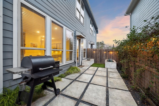 patio terrace at dusk featuring grilling area