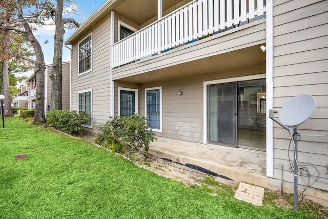 rear view of house with a balcony and a lawn