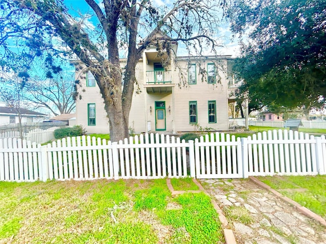 view of front of house with a front yard and a balcony