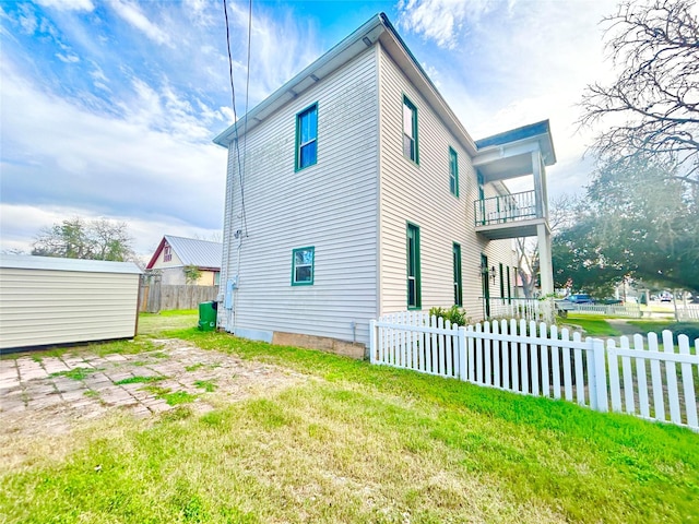 view of property exterior featuring a balcony and a yard