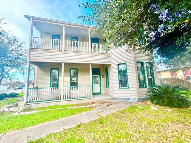 view of front of house featuring a balcony, a front lawn, and a porch