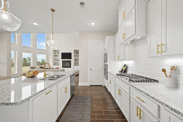 kitchen featuring pendant lighting, appliances with stainless steel finishes, white cabinetry, sink, and a center island with sink