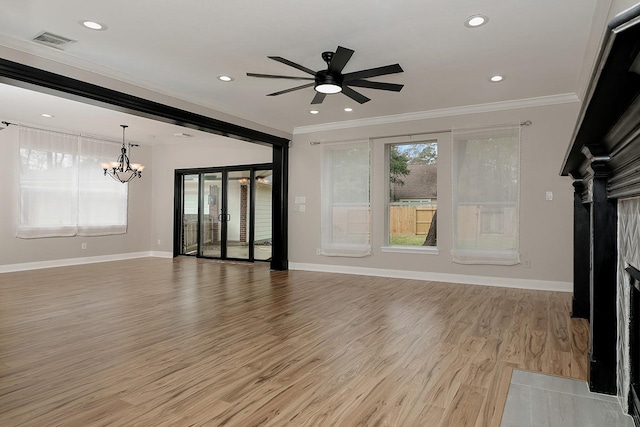 unfurnished living room featuring light wood-type flooring, ceiling fan with notable chandelier, a healthy amount of sunlight, and crown molding