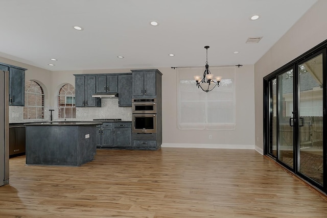 kitchen featuring gas stovetop, hanging light fixtures, tasteful backsplash, and light wood-type flooring