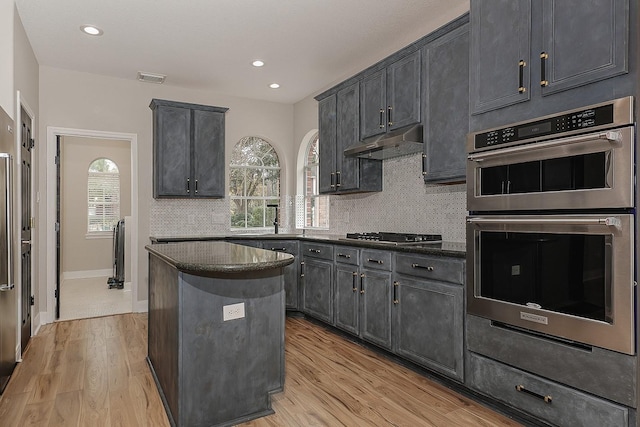 kitchen with a center island, light hardwood / wood-style floors, appliances with stainless steel finishes, sink, and backsplash