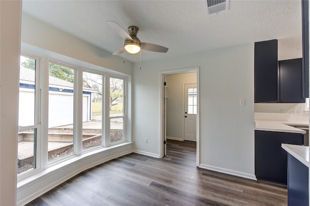 unfurnished dining area with ceiling fan, a wealth of natural light, dark hardwood / wood-style floors, and a textured ceiling