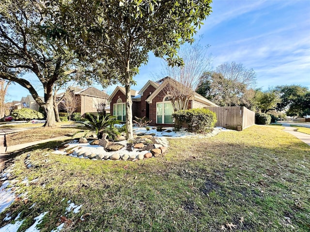 view of front of home featuring a front yard, brick siding, and fence