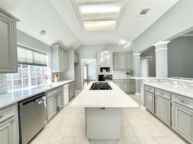 kitchen featuring a sink, visible vents, light countertops, a center island, and black appliances