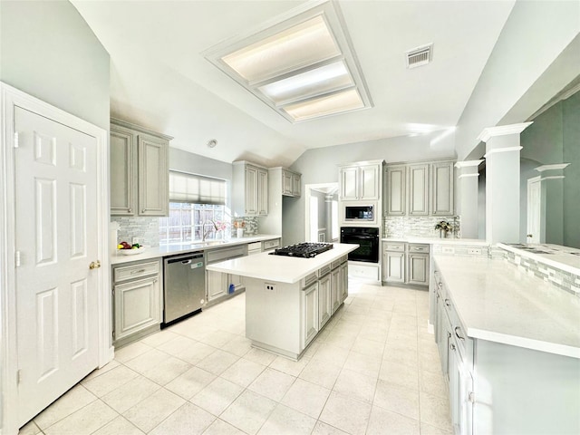 kitchen with stainless steel appliances, a kitchen island, visible vents, vaulted ceiling, and light countertops