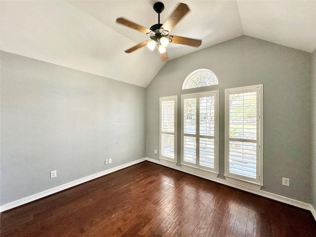 spare room with lofted ceiling, dark wood finished floors, a ceiling fan, and baseboards