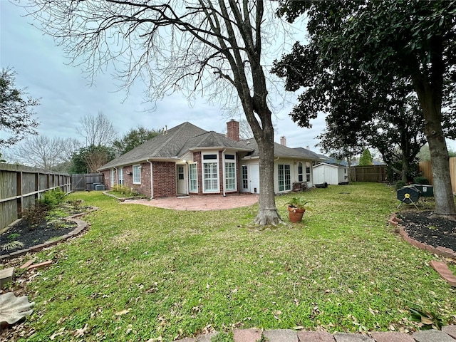 back of property with a patio area, a fenced backyard, a lawn, and brick siding