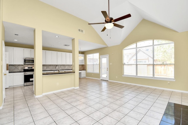 unfurnished living room featuring high vaulted ceiling, sink, light tile patterned floors, and ceiling fan