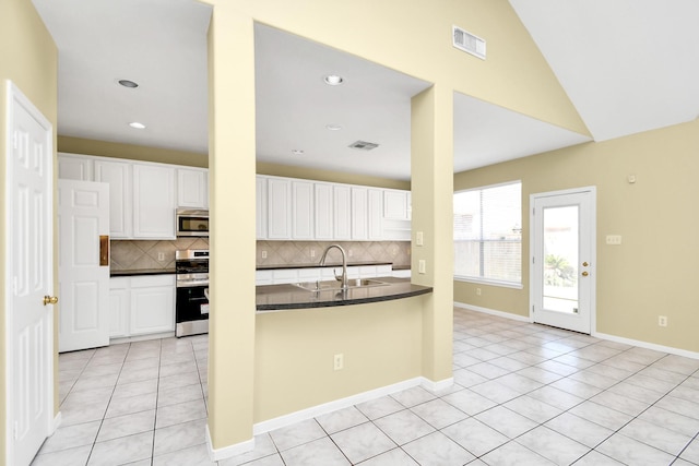 kitchen featuring white cabinets, backsplash, appliances with stainless steel finishes, and lofted ceiling