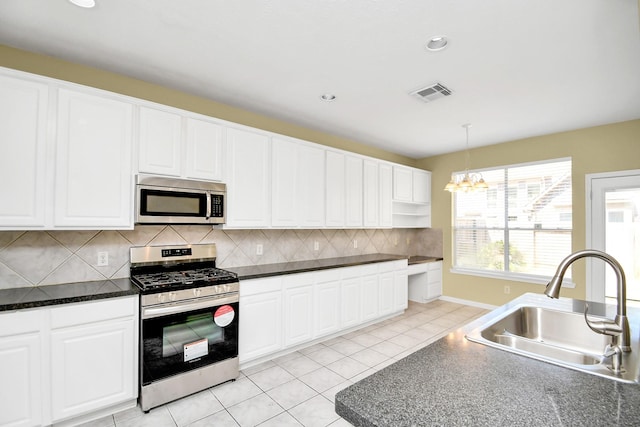 kitchen with appliances with stainless steel finishes, hanging light fixtures, sink, white cabinets, and light tile patterned flooring