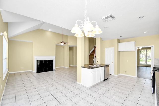 kitchen featuring stainless steel dishwasher, hanging light fixtures, sink, a tile fireplace, and light tile patterned flooring