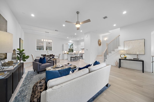 living room featuring light hardwood / wood-style floors and ceiling fan with notable chandelier