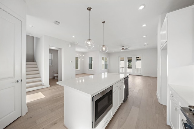 kitchen featuring white cabinets, a center island, hanging light fixtures, and built in microwave