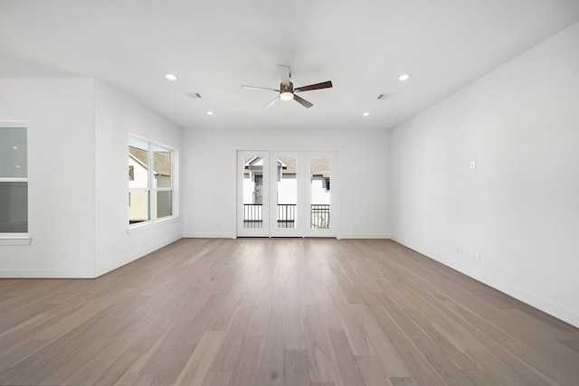 unfurnished living room with light hardwood / wood-style floors, a wealth of natural light, ceiling fan, and french doors