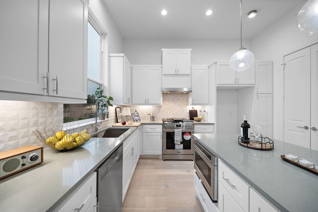 kitchen with light stone countertops, white cabinetry, decorative backsplash, pendant lighting, and stainless steel appliances