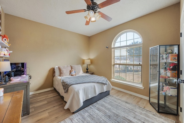 bedroom featuring a ceiling fan, baseboards, and light wood-style floors