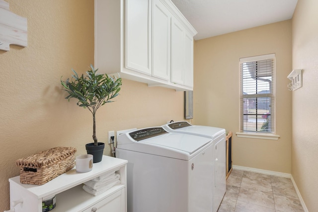 clothes washing area featuring baseboards, washer and clothes dryer, and cabinet space