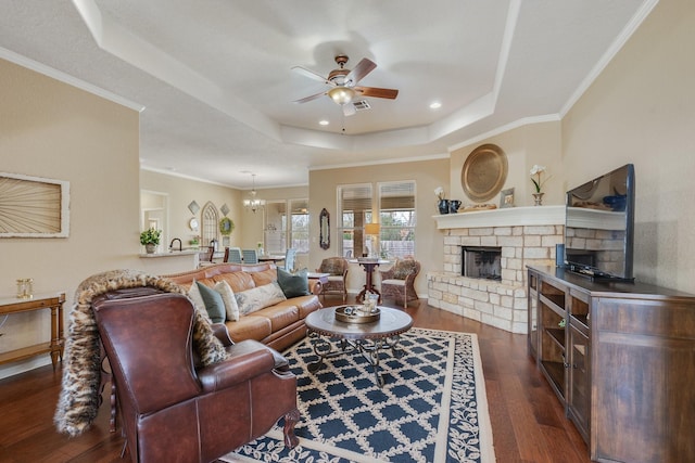 living area with a tray ceiling, dark wood-style floors, visible vents, ceiling fan, and a fireplace