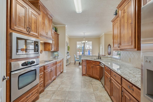 kitchen with stainless steel appliances, a peninsula, a chandelier, backsplash, and brown cabinets