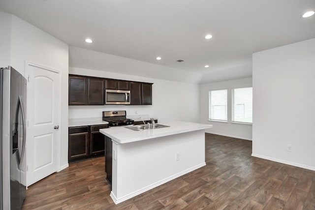 kitchen with sink, a kitchen island with sink, appliances with stainless steel finishes, and dark wood-type flooring