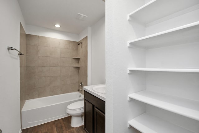 full bathroom featuring vanity, hardwood / wood-style flooring, tiled shower / bath, and toilet