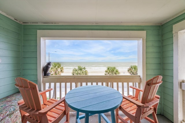 sunroom with a water view and a view of the beach