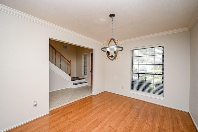 empty room featuring wood-type flooring, an inviting chandelier, and ornamental molding