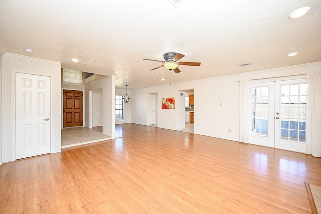 unfurnished living room featuring ceiling fan, crown molding, french doors, and light wood-type flooring