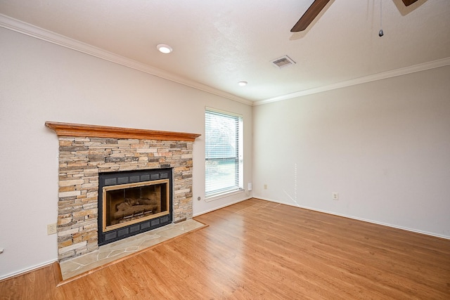 unfurnished living room with crown molding, hardwood / wood-style flooring, ceiling fan, and a stone fireplace