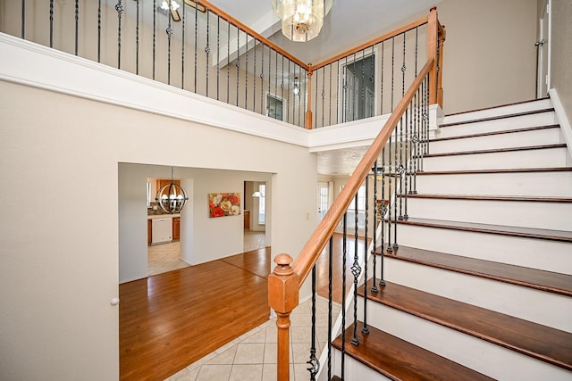 staircase featuring a notable chandelier, a towering ceiling, and tile patterned flooring