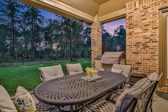 patio terrace at dusk with a gazebo, a lawn, and area for grilling