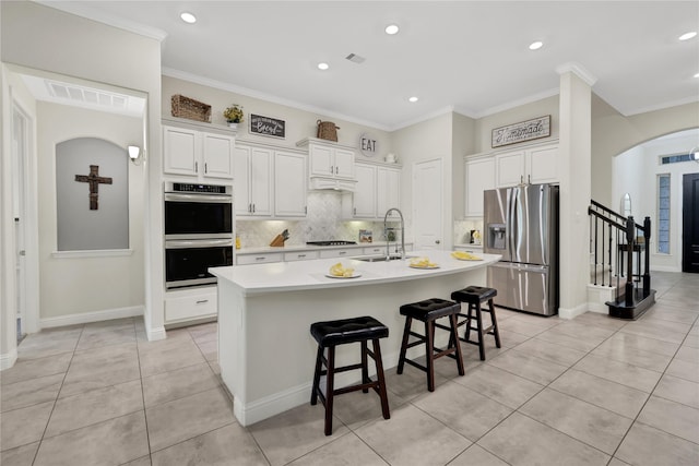 kitchen featuring sink, white cabinets, a breakfast bar, an island with sink, and stainless steel appliances