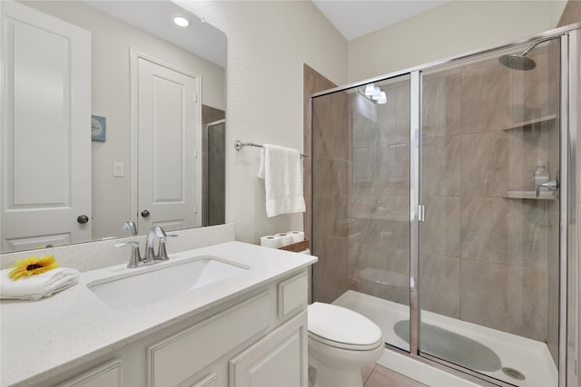 bathroom with vanity, a shower with shower door, tile patterned floors, and toilet