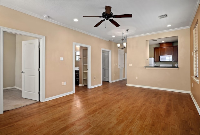 unfurnished living room with ceiling fan with notable chandelier, wood-type flooring, and ornamental molding