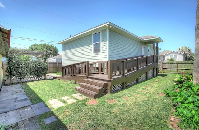 rear view of property with a wooden deck and a lawn