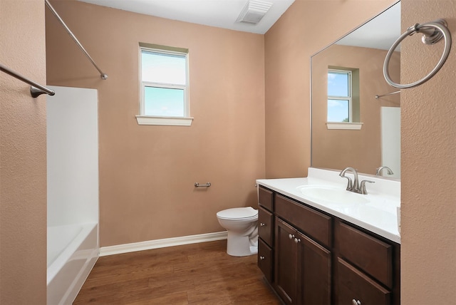 full bathroom featuring washtub / shower combination, wood-type flooring, toilet, and vanity