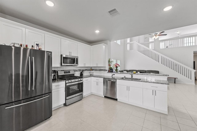 kitchen featuring appliances with stainless steel finishes, white cabinetry, sink, kitchen peninsula, and dark stone counters